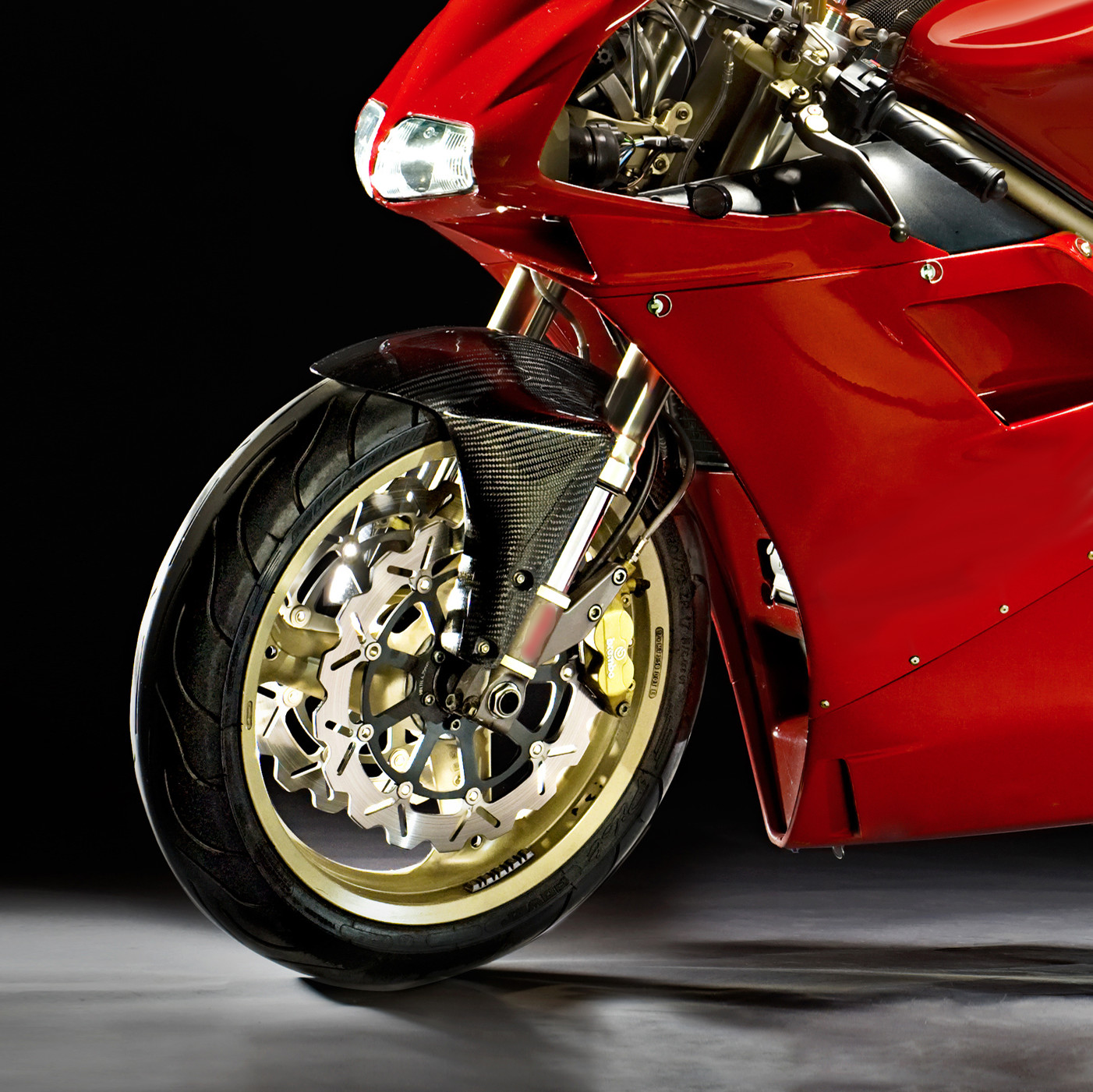 Front end of Red Motorcycle featuring gold rim on front tire